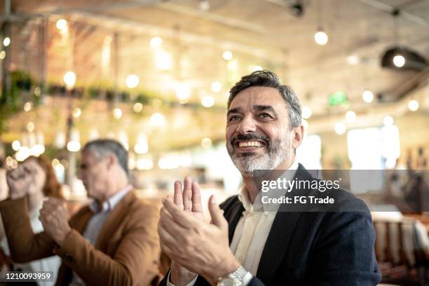 mature businessman applauding at business meeting - awards ceremony table stock pictures, royalty-free photos & images