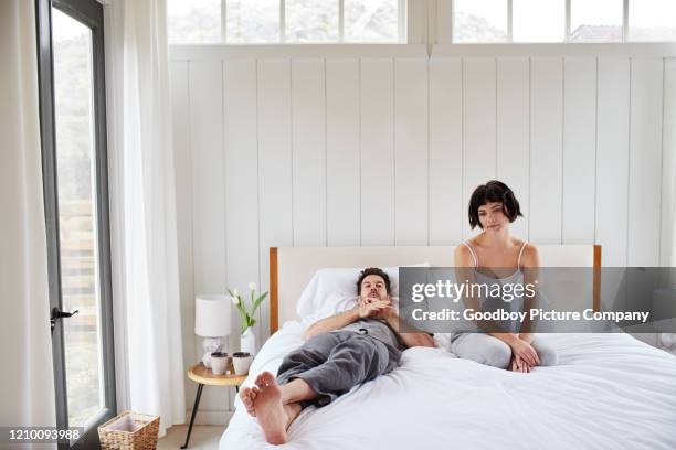 young couple sitting in silence on their bed in the morning - bored girlfriend stock pictures, royalty-free photos & images