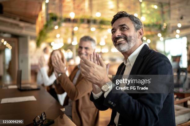 mature businessman applauding at business meeting - awards ceremony table stock pictures, royalty-free photos & images