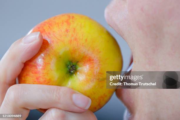 Symbolic photograph. A woman bites into an apple on April 13, 2020 in Berlin, Germany.