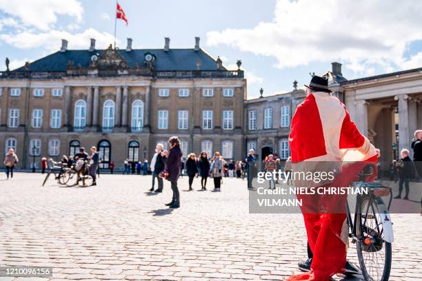 Man wrapped into a Danish flag stands at Amalienborg Palace Square, where people sang to mark the 80th birthday of Danish Queen Margrethe II, in...