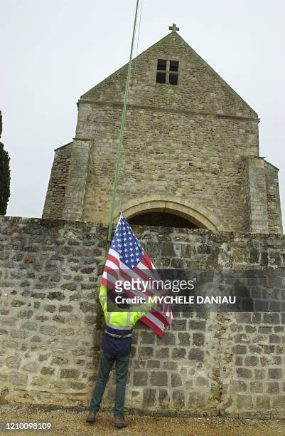 Une personne ajuste le drapeau américain le 06 février 2004 sur le mur de l'église de Graignes transformé en mémorial des victimes de la Seconde...