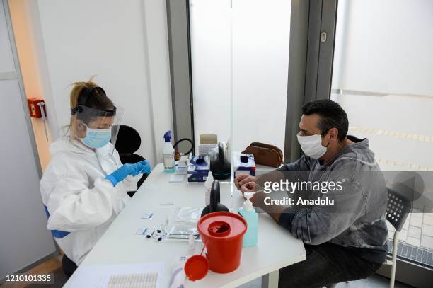 Health worker wearing a protective medical equipment extracts blood from a patient to make an antibody test for COVID-19 at the Dworska Hospital in...