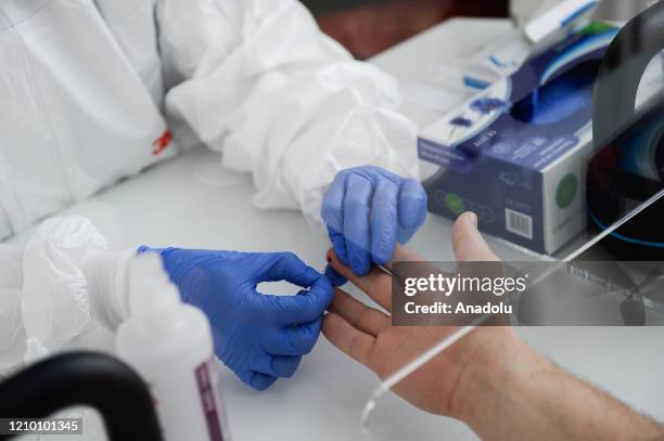 Health worker wearing a protective medical equipment extracts blood from a patient to make an antibody test for COVID-19 at the Dworska Hospital in...