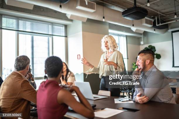 de onderneemster die van de leider aan zijn collega's op presentatie spreekt - gender equality stockfoto's en -beelden