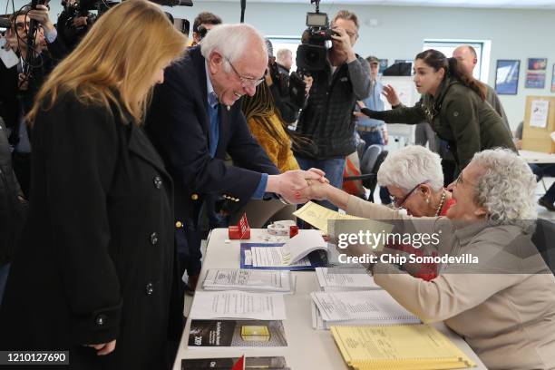 Democratic presidential candidate Sen. Bernie Sanders and his wife Jane O'Meara Sanders greet poll workers before voting in their state's primary...