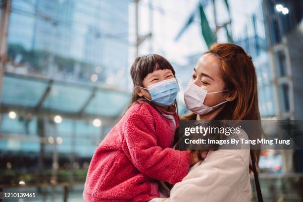 mom & daughter in medical face masks talking joyfully in train station - protective face mask happy stock pictures, royalty-free photos & images