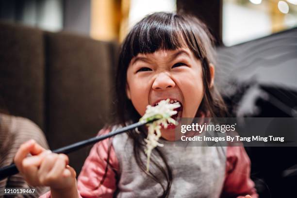 little girl having meal joyfully with mom in restaurant - restaurant kids stock-fotos und bilder