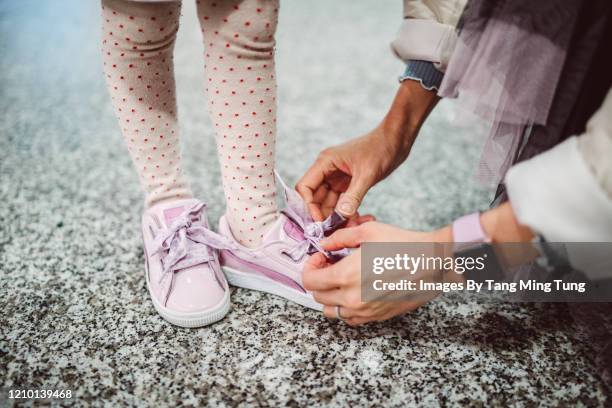 mom helping little girl to tide her shoelace - stringa foto e immagini stock