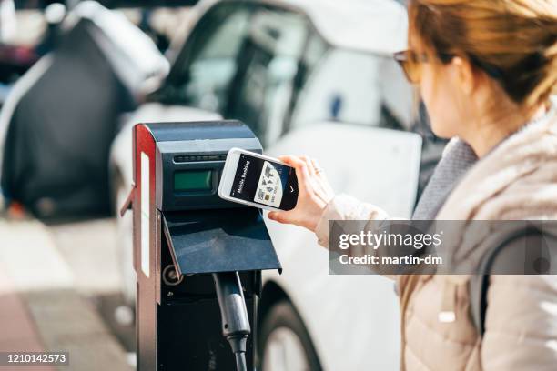 woman paying contactless for charging an electric car - smart city life stock pictures, royalty-free photos & images