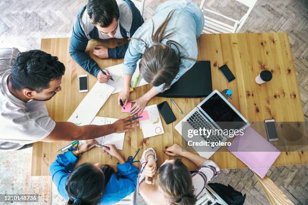 overhead view on business people working together on desk - communication strategy stock pictures, royalty-free photos & images