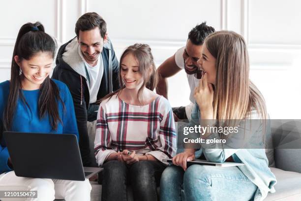 vijf jonge mensen die laptop op bank bekijken - aftrappen stockfoto's en -beelden