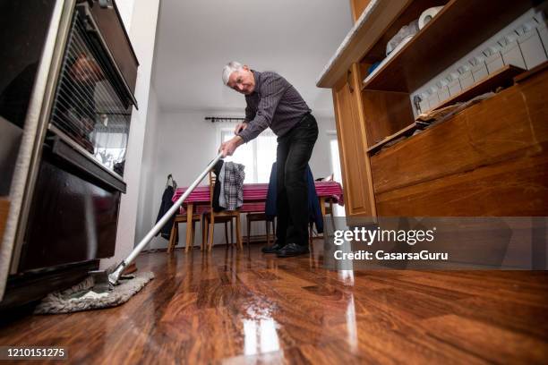 senior adult man cleaning floor with a mop - stock photo - mop stock pictures, royalty-free photos & images