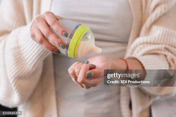 une mère méconnaissable teste la température d’un biberon - bébé biberon photos et images de collection
