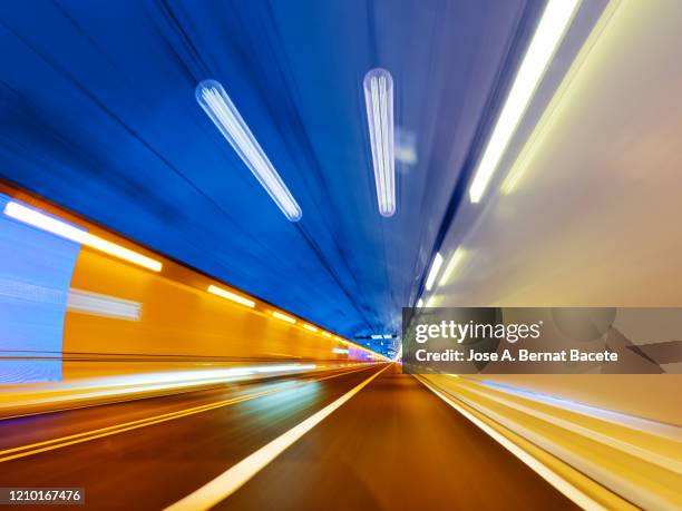 driving a car at high speed inside of an illuminated tunnel. - bande médiane photos et images de collection