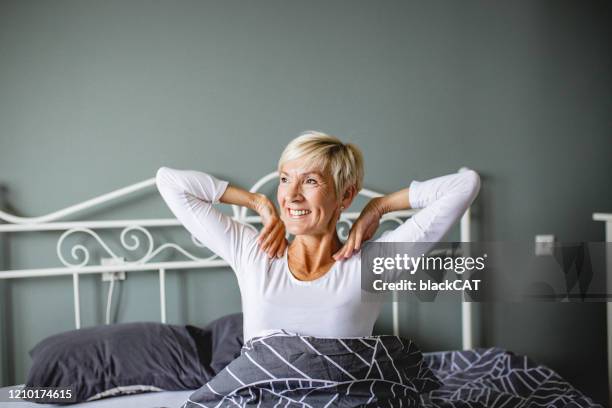 hogere vrouw die omhoog ontwaakt - old bed stockfoto's en -beelden