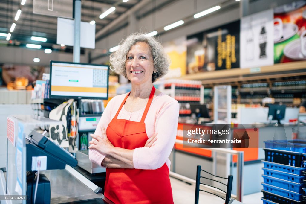 Seniorin arbeitet als Kassiererin im Supermarkt
