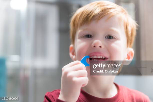 little redhead boy flossing his teeth - dental floss stock pictures, royalty-free photos & images