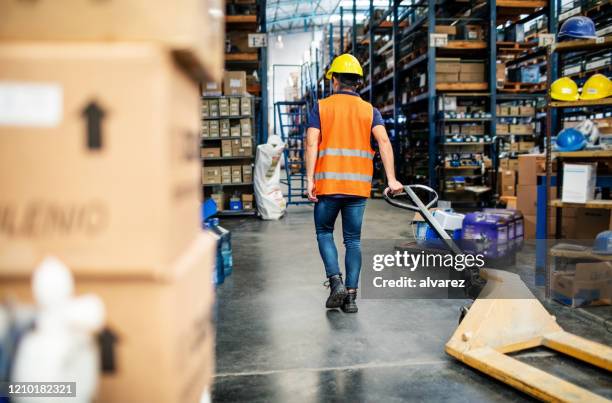 worker pulling a hand truck in warehouse - helmet cart stock pictures, royalty-free photos & images