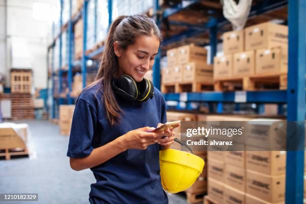 de pakhuisarbeider van de vrouw die mobiele telefoon gebruikt - arbeider stockfoto's en -beelden