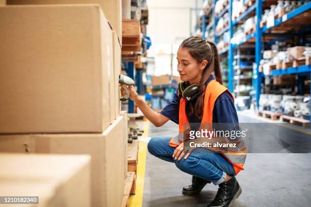 female worker scanning boxes in warehouse rack - storage room stock pictures, royalty-free photos & images