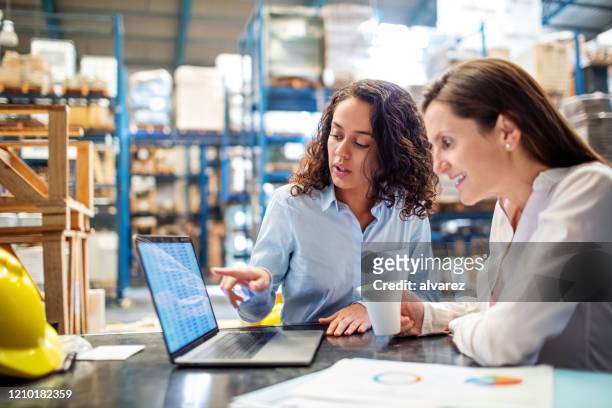 woman showing inventory on laptop to warehouse manager - gerente imagens e fotografias de stock