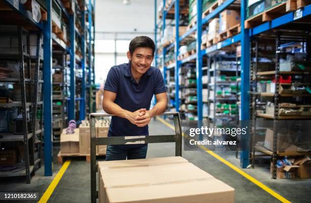 lagerarbeiter mit trolley im gang - warehouse worker stock-fotos und bilder