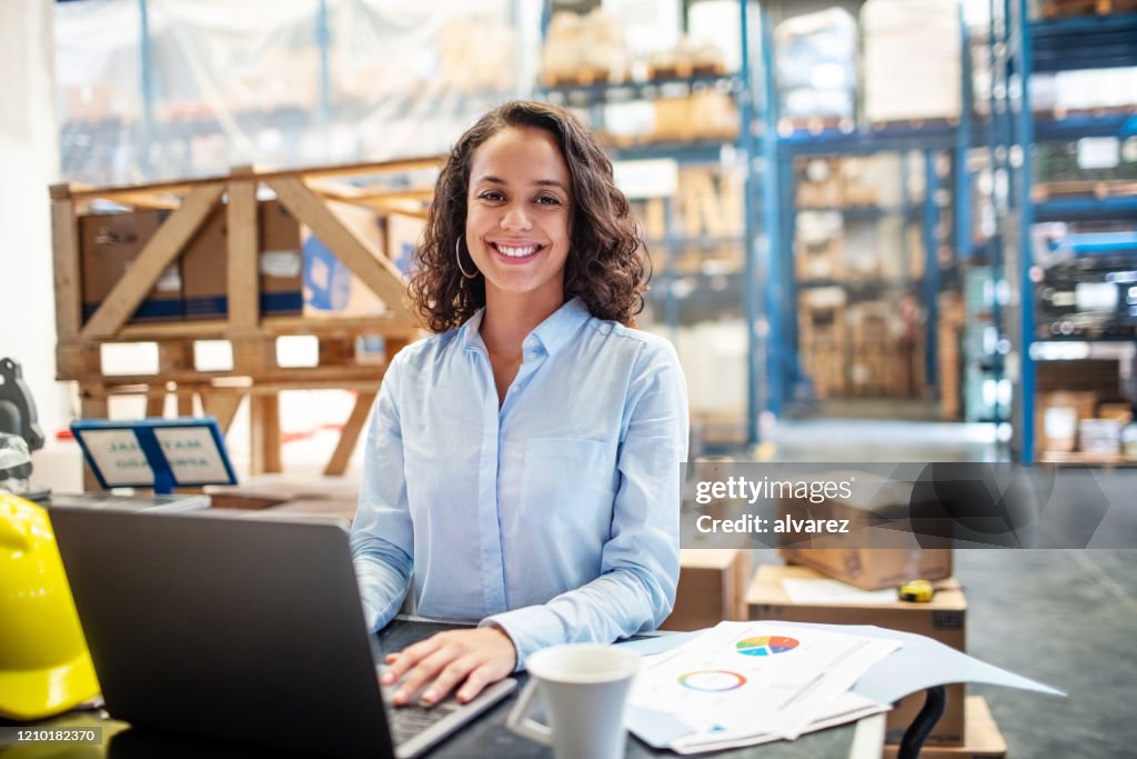 Businesswoman with a laptop working at warehouse