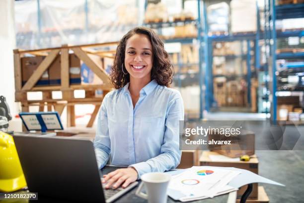 businesswoman with a laptop working at warehouse - boss lady stock pictures, royalty-free photos & images