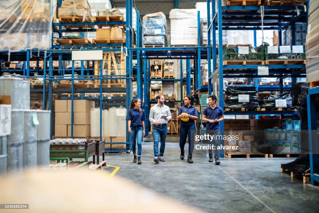 Warehouse employees walking through aisle and talking