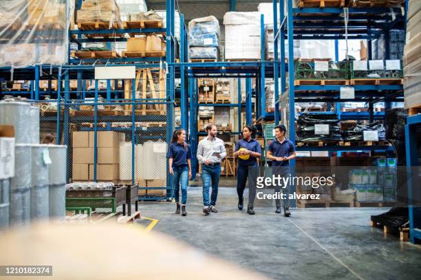 warehouse employees walking through aisle and talking - factory imagens e fotografias de stock