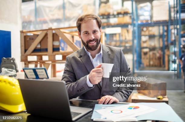 lächelnder geschäftsmann mit kaffeepause im lager - baumarkt mitarbeiter stock-fotos und bilder
