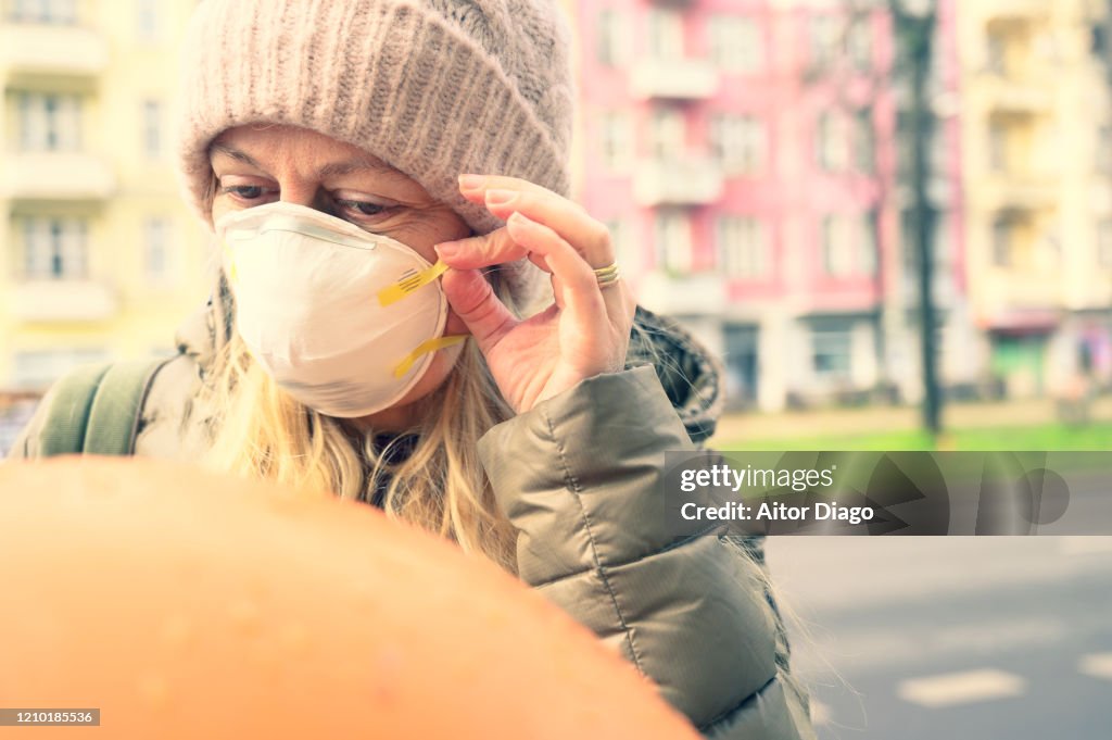 Woman in the street putting a protection mask on. Berlin, Germany.