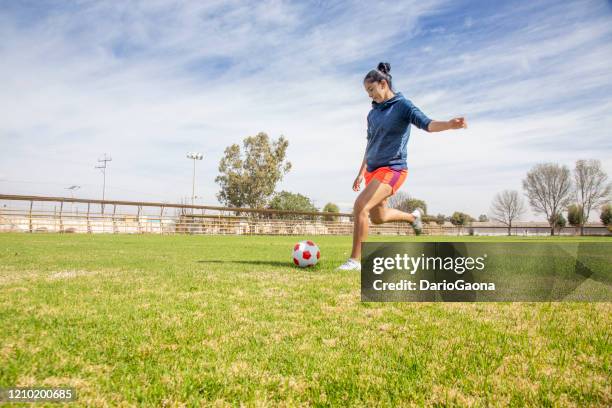 junge latinos, die fußball spielen - shooting at goal stock-fotos und bilder