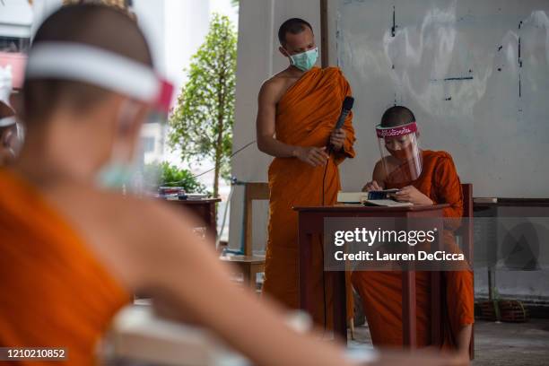 Monks wear face maks and face shields to protect themselves from the coronavirus during their Pali language course at Wat Molilokkayaramon April 17,...