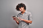 Smiling arabian young man looking at his digital tablet screen