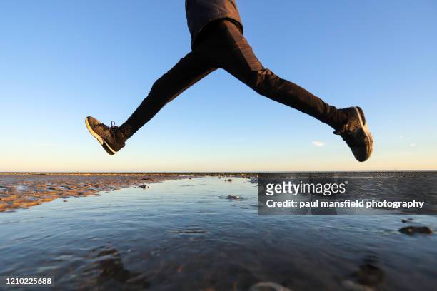 low angle view of boy jumping - leap of faith modo di dire inglese foto e immagini stock