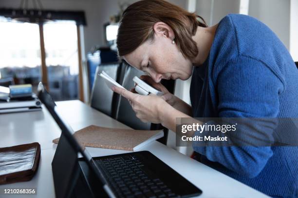 blind woman reading document through magnifying glass while sitting at home - color blindness fotografías e imágenes de stock