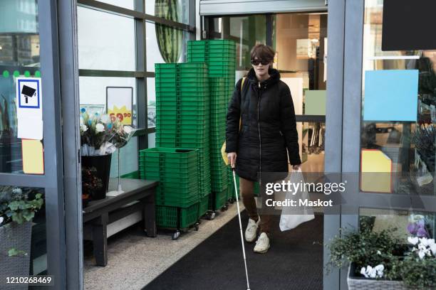 full length of blind woman shopping while walking with stick in supermarket - blindness imagens e fotografias de stock