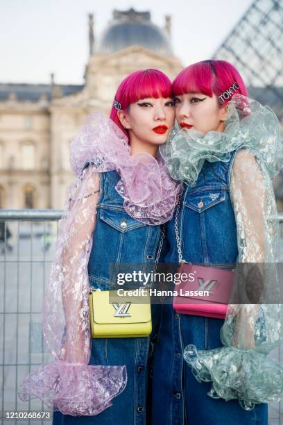 Ami Suzuki and Aya Suzuki of Amiaya wearing Louis Vuitton denim dress, neon pink bag and organza frill shirt outside the Louis Vuitton show during...