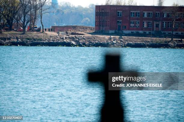 People work next to a trench on Hart Island amid the coronavirus pandemic, seen from City Island on April 17, 2020 in New York City. - As New York...