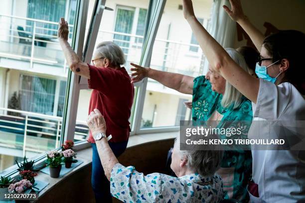 Staff members and residents salute their families at the elderly residence Christalain on April 17 in Brussels, during a strict lockdown in the...