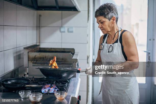senior female chef cooking - stir frying european stock pictures, royalty-free photos & images