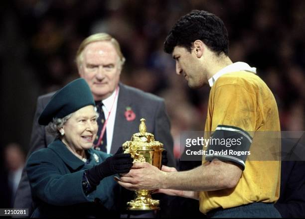 Australia captain John Eales receives the Web Ellis trophy from Her Majesty the Queen after victory over France in the Rugby World Cup Final at the...