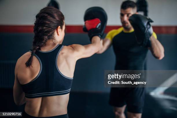 jonge vrouw op de praktijk van de kickbox, die van haar bus leert terwijl het sparren met hem - self defense stockfoto's en -beelden