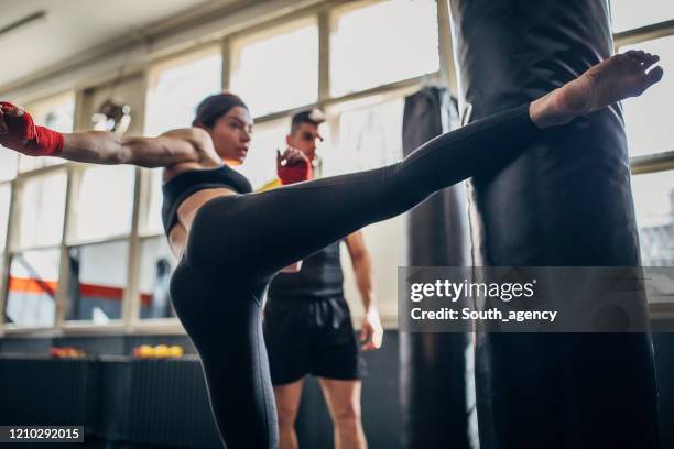 kick-box-lehrer suchen, wie frau kick boxer tritt boxsack auf kick-box-klasse - sparring training stock-fotos und bilder