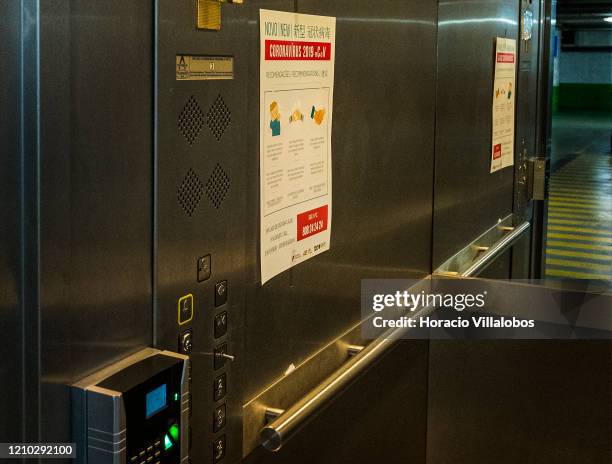 Trilingual poster, in Portuguese, English and Chinese, with instructions on Coronavirus prevention hangs in the interior of an elevator at the Loja...