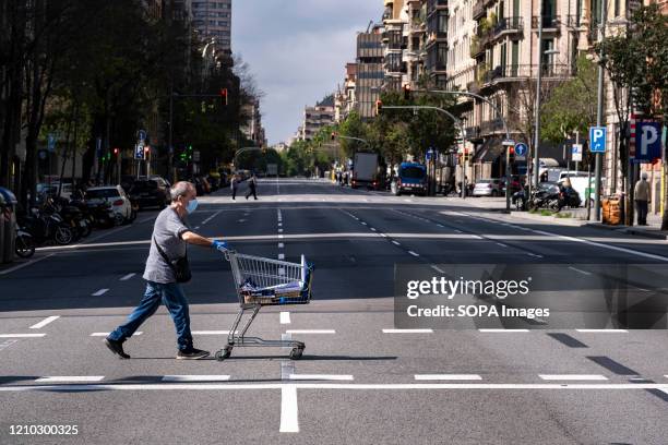 Man crosses the deserted Aragón street pushing a supermarket cart during confinement. Barcelona overcomes a month of home confinement and social...