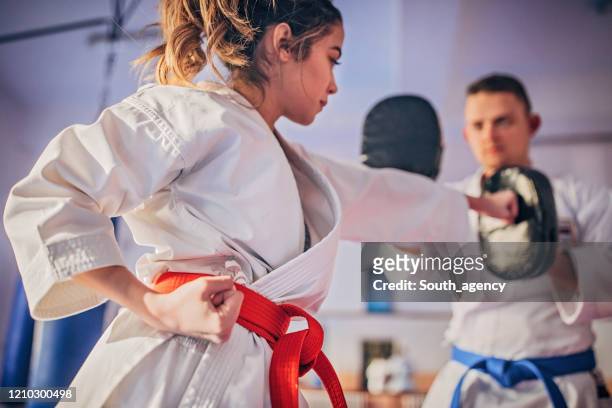 karatespielerin übt mit trainer - verteidigen stock-fotos und bilder
