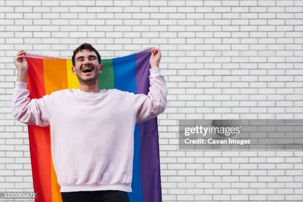 happy gay man with a rainbow flag - gay flag stockfoto's en -beelden